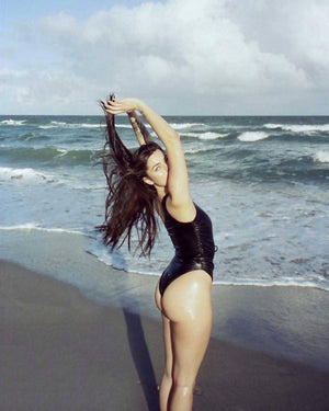 Woman wearing black leather onepiece swimsuit + whit